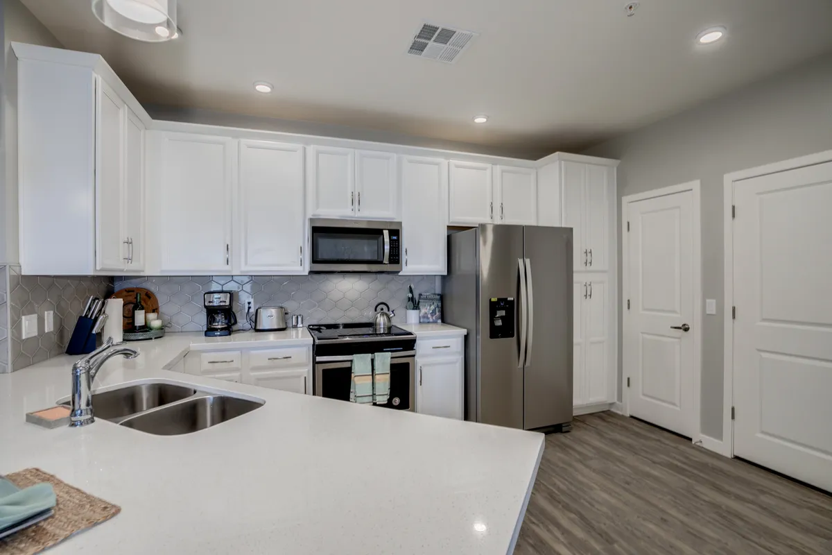 A modern kitchen with stainless steel appliances, a kitchen island, white cabinetry, and a sleek countertop. The space is well-lit and inviting, ideal for meal preparation, dining, and entertaining guests.