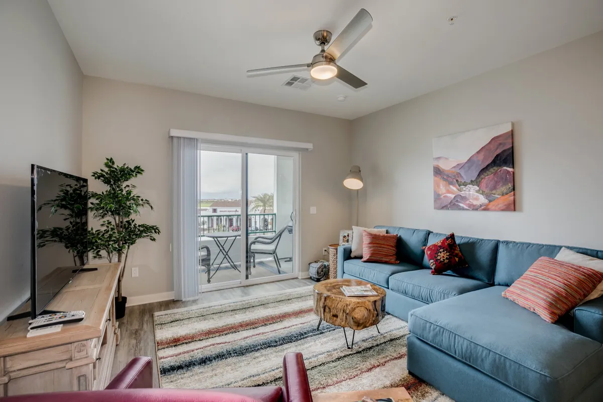 A comfortable living area featuring a plush sofa, a coffee table, a television, and a window offering a glimpse of the outdoors. The soft natural light filtering in through the window adds a welcoming atmosphere, emphasizing the transition between indoor relaxation and the possibility of stepping outside to explore.