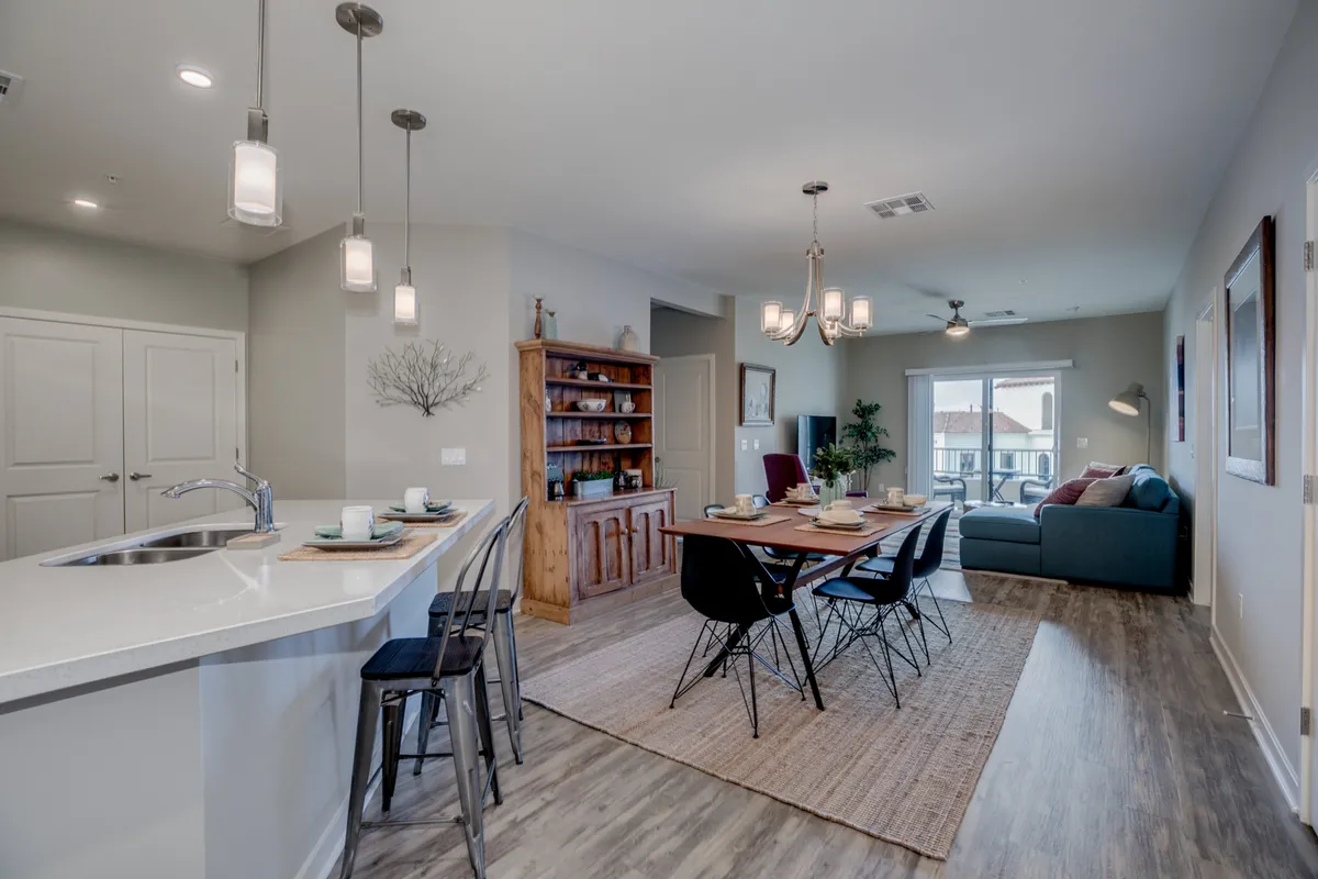 This inviting and cozy scene showcases a dining table set for a meal, stylish lighting, a comfortable couch, and a wooden sideboard. The setting suggests a space ideal for shared meals, relaxation, and celebrations with friends or partners.